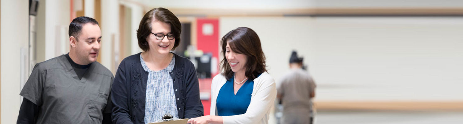 Health professionals smiling at clipboard while standing in hallway